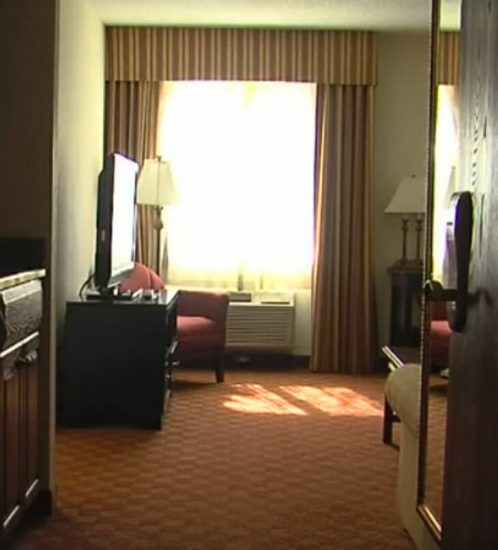 Limpiadora del hotel abre cómoda en la habitación de la pareja mayor